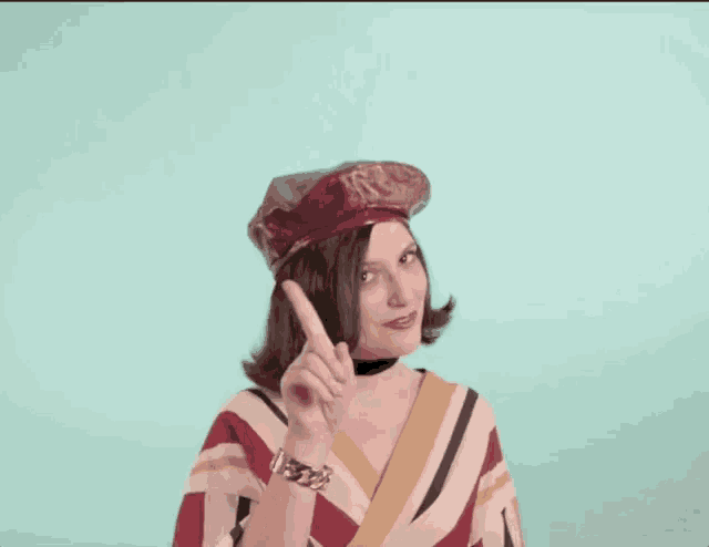 a woman wearing a red hat and a striped shirt is pointing up