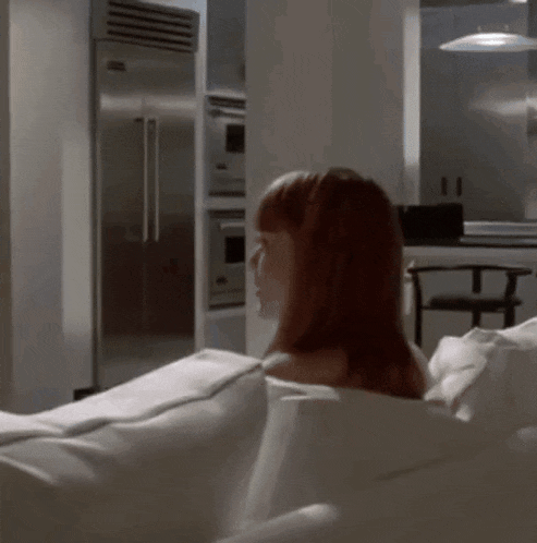 a woman sits on a white couch in a kitchen