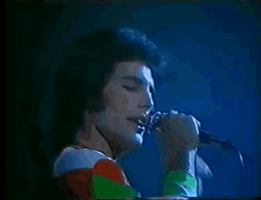 a man is singing into a microphone in front of a blue background .