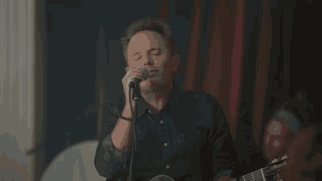 a close up of a person playing a keyboard with a microphone in the background
