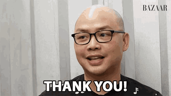 a man wearing glasses says thank you in front of a wall