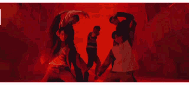 a group of people are dancing in a dark room with a red background