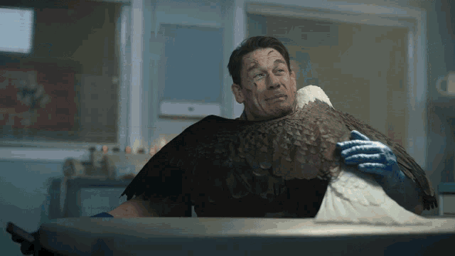 a man is holding a large bird with its wings spread