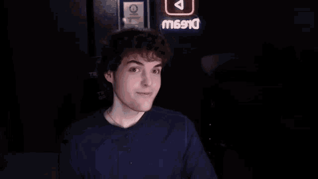 a young man in a blue shirt is holding a stuffed animal with a smiling face on it .