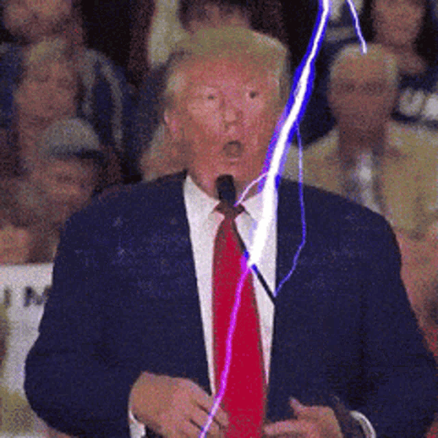 a man in a suit and tie is talking into a microphone with a lightning bolt coming out of his mouth