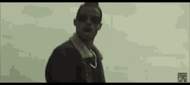 a man wearing sunglasses is standing in front of a cloudy sky ..