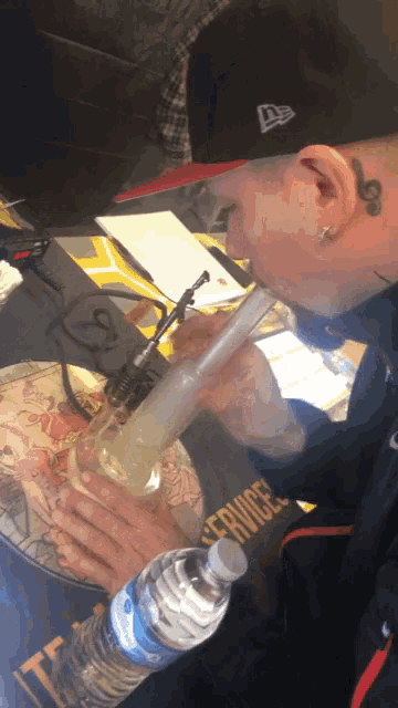 a man is smoking a bong with a bottle of water in front of him