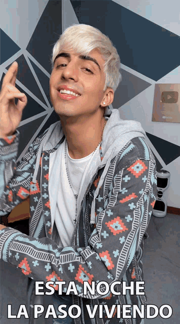 a young man with blonde hair is wearing a jacket that says esta noche la paso vivendo
