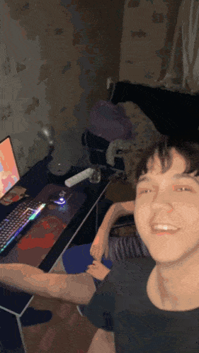a man is sitting in front of a computer and smiling at the camera
