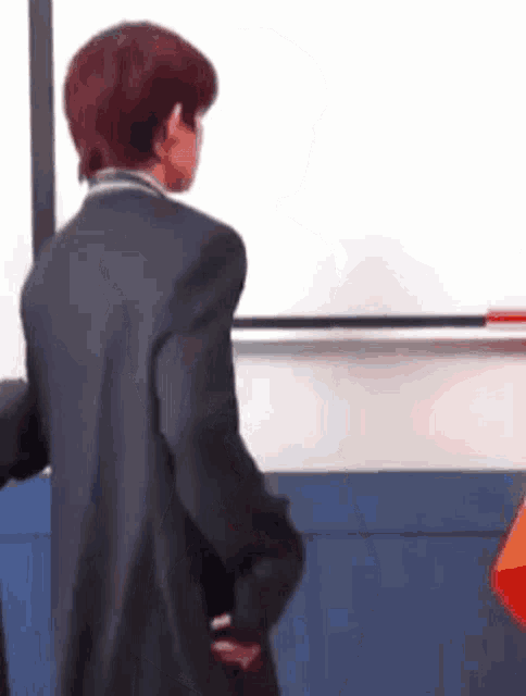 a man in a suit is standing in front of a whiteboard in a room .