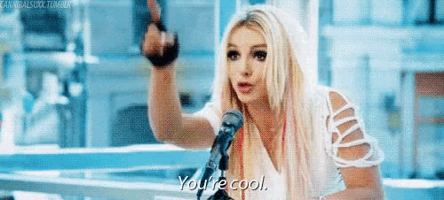 a blonde woman is standing in front of a microphone and says you 're cool .