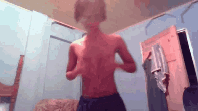 a shirtless boy stands in a room with a door open