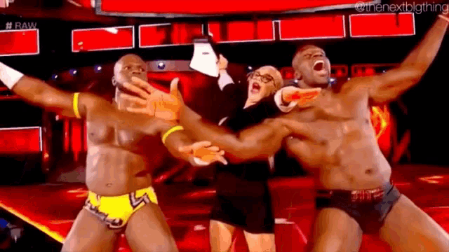 a group of wrestlers are standing on a stage with their arms outstretched .