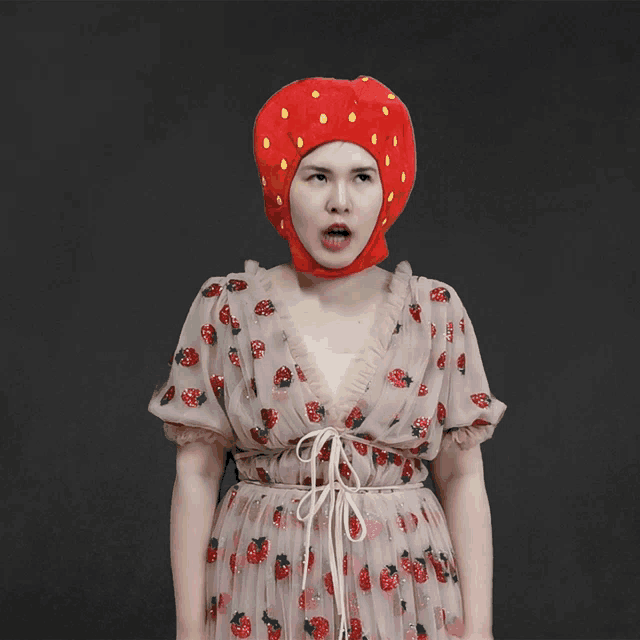 a woman wearing a strawberry hat and a strawberry dress