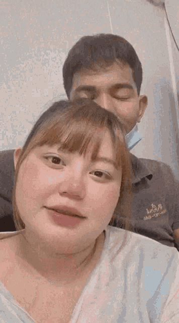 a man and a woman are standing next to each other and making funny faces . the woman is wearing a mask .