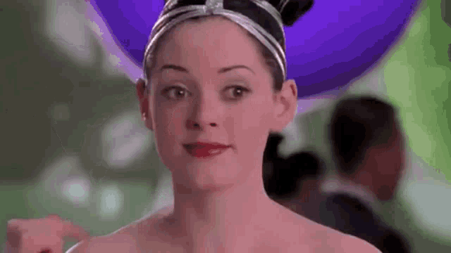 a woman wearing a purple hat and red lipstick is smiling .