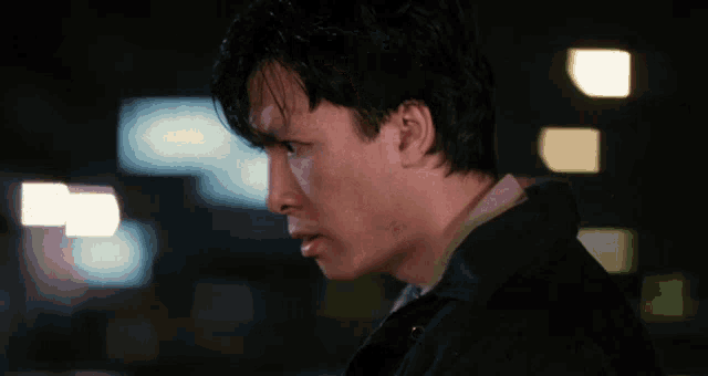a man in a black jacket stands in front of a blurry background