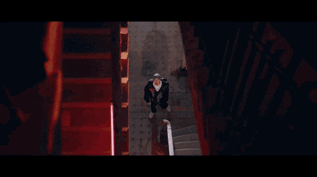 a person walking down a set of stairs with a red light behind them