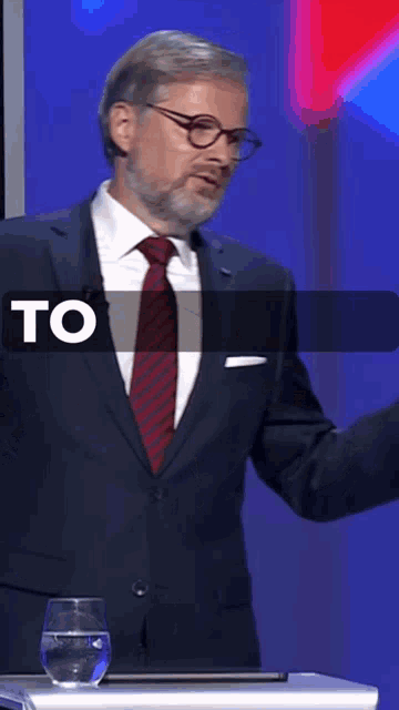a man in a suit and tie is standing at a podium with the word to visible