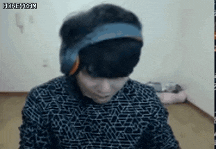 a man wearing headphones and a headband is sitting in front of a computer screen .