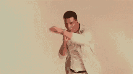 a man in a white shirt and tie is dancing in front of a white wall .