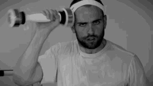 a man wearing a headband is holding a dumbbell over his ear