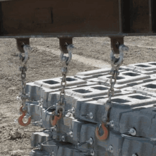 a stack of concrete blocks is being lifted by a crane with a hook attached to it