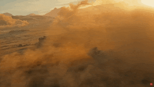 an aerial view of a desert landscape with smoke coming out of the ground