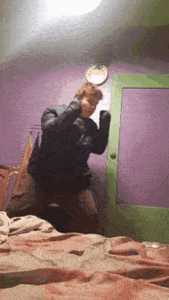 a man in a black jacket is standing in front of a purple wall and a green door