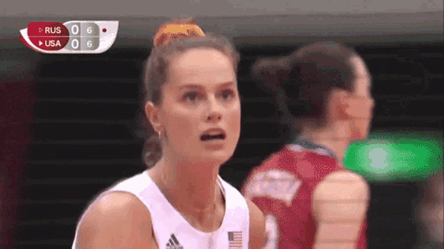 a female volleyball player stands in front of a scoreboard that says ' rus 0-6 usa 0-6 '