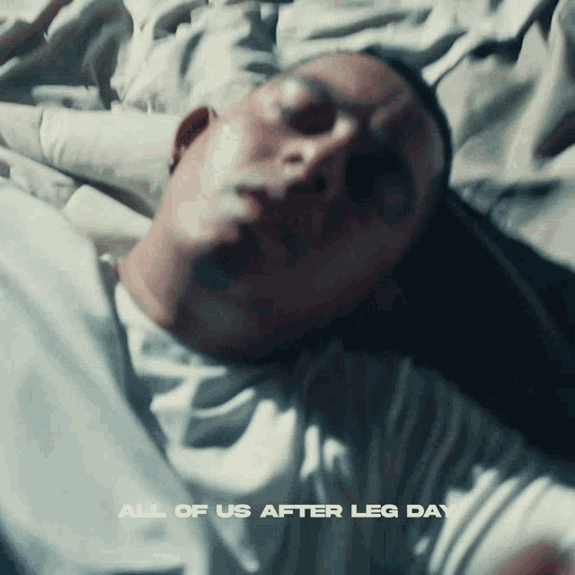 a man is laying on a bed with the words " all of us after leg day " above him