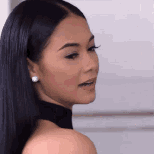 a close up of a woman 's face with long black hair and earrings