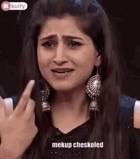 a woman wearing earrings is making a funny face and pointing her finger at the camera .