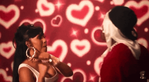 a man in a santa suit kisses a woman in front of a wall with hearts on it