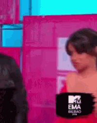 a woman in a red dress is standing in front of a mtv ema sign .