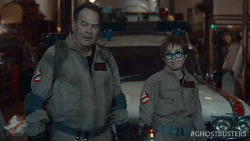 two ghostbusters are standing next to each other