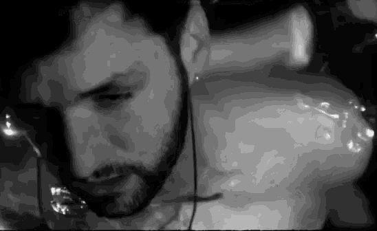 a black and white photo of a man with a beard swimming in a pool