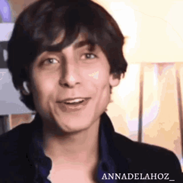 a close up of a young man making a funny face while wearing a black jacket .