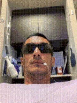 a man wearing sunglasses and a cigarette in his mouth is laying on a bed
