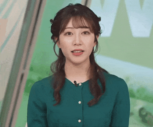 a woman in a green shirt with a microphone on her neck is smiling