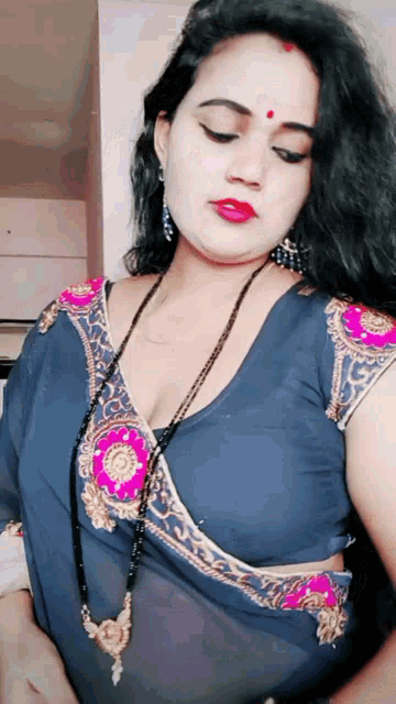 a woman wearing a blue blouse and a pink necklace