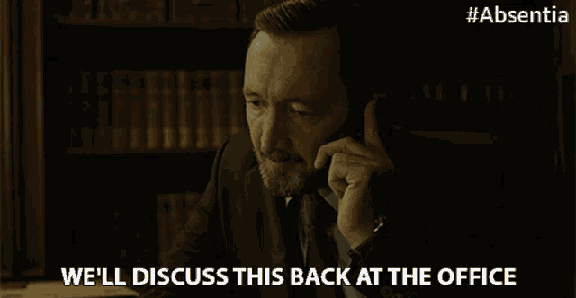 a man in a suit and tie talking on a cell phone with the words we 'll discuss this back at the office below him