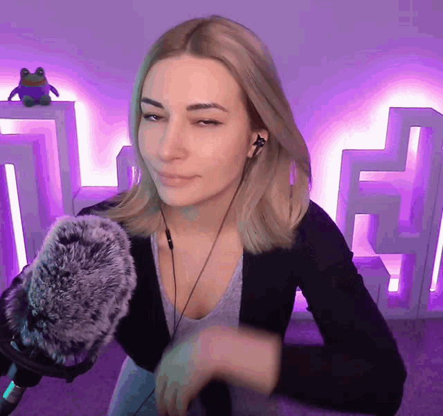 a woman wearing headphones stands in front of a microphone in front of a frog