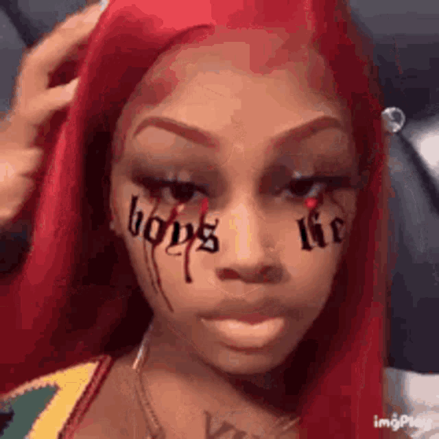 a woman with red hair has a tattoo on her face that says `` boys life '' .
