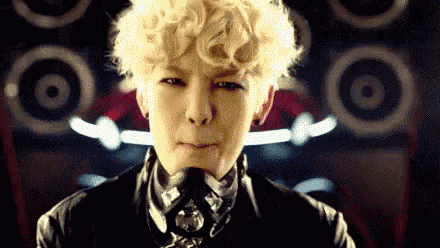 a young man with blonde curly hair is wearing a black leather jacket and tie .
