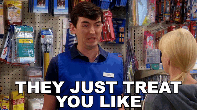 a man in a blue vest is talking to a woman in front of a sign that says " they just treat you like "