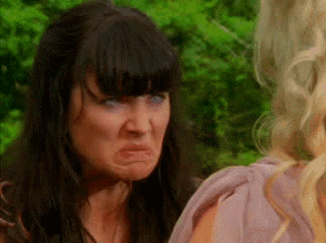 a woman making a funny face while standing next to another woman .