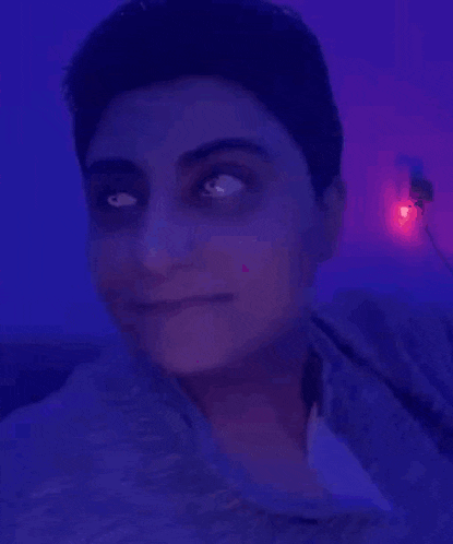 a woman is making a funny face in front of a blue light .
