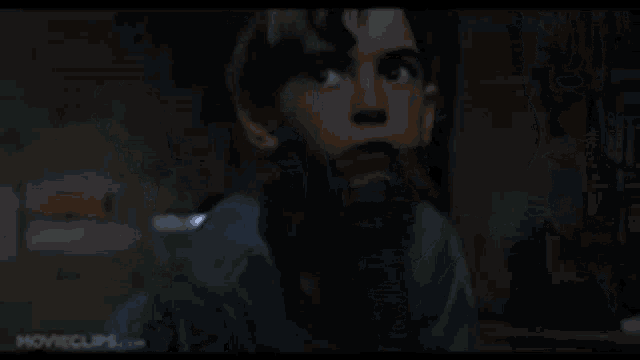 a close up of a young boy 's face in a dark room with a blurred background .