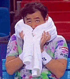a man covering his face with a white towel and a shirt that says yonex